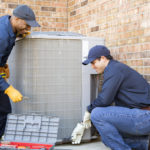 Multi-ethnic team of blue collar air conditioner repairmen at work.